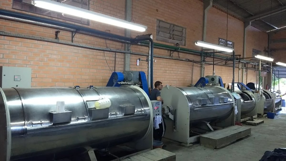 Máquinas industriais de lavação alinhadas no galpão da lavanderia