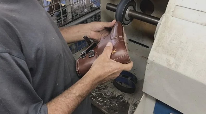 Artesão fazendo o acabamento de uma bota KING55 na bancada do Studio55