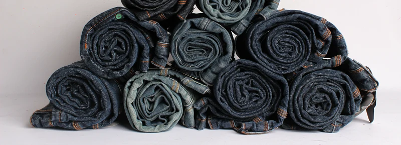 Pilha de calças jeans KING55 enroladas, recebidas pelo programa Ex-Jeans